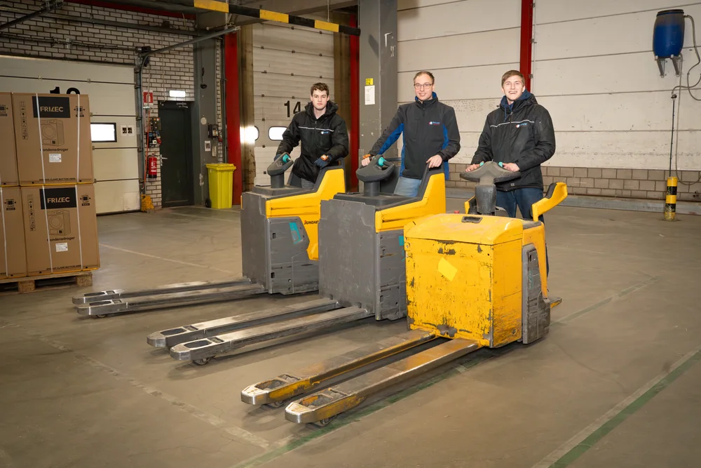 Drie collega's van Bouw met pallettrucks in het magazijn